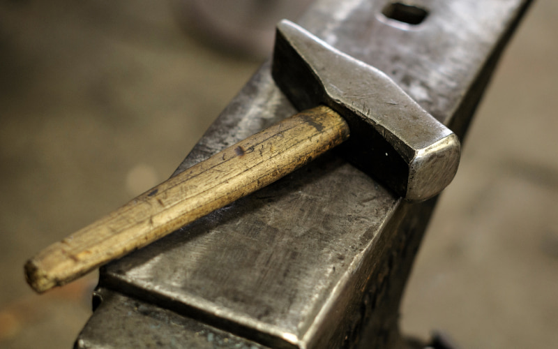 Blacksmithing hammer resting on anvil
