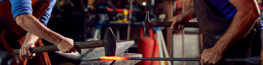 Bladesmithing master assisting a student