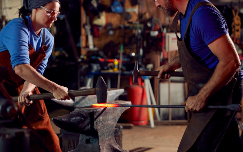Bladesmithing master assisting a student