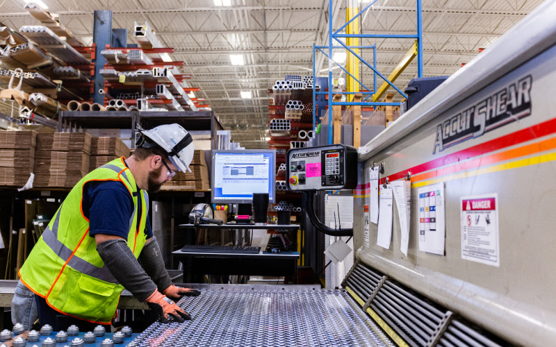 OlM warehouse employee cutting sheet metal on accushear