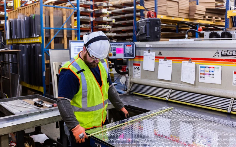 Olm warehouse employee prepping sheet metal for a custom cut
