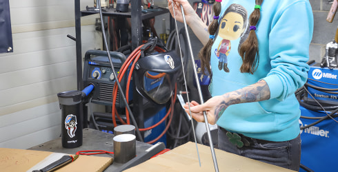 Barbie prepping a piece of metal for the welding process