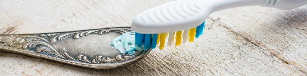 Scrubbing an old spoon with a toothbrush
