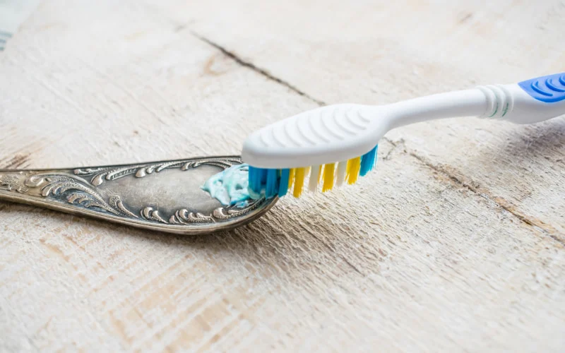 Scrubbing an old spoon with a toothbrush