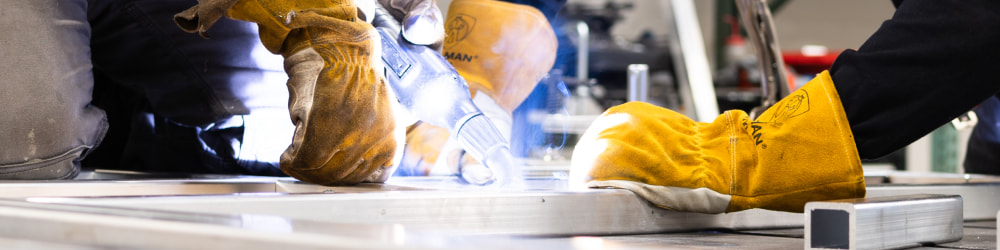 Two Welders welding a piece of aluminum