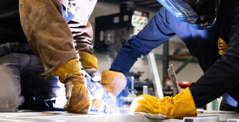 Two weldes welding pieces of aluminum
